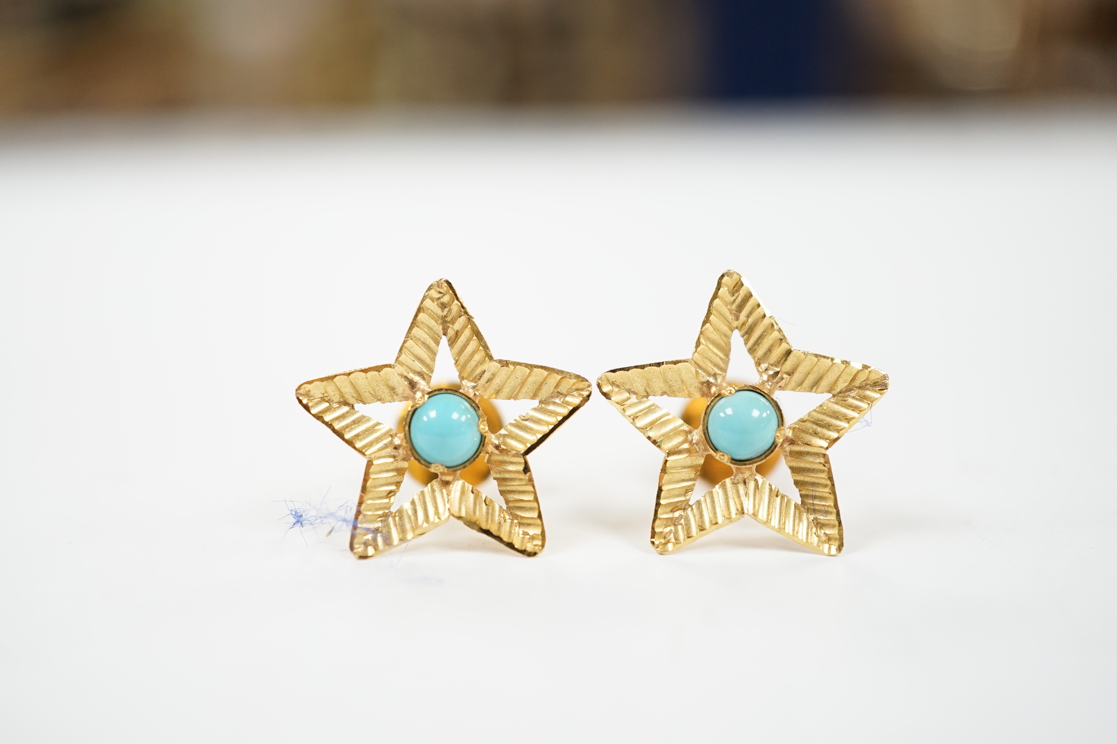 A pair of yellow metal and single stone turquoise set star earrings, 15mm, gross weight 2.4 grams.